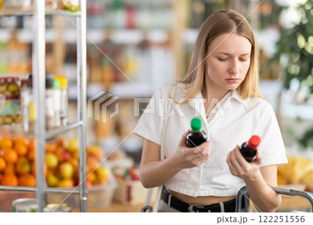 Young woman choosing soy sauce in grocery 122251556