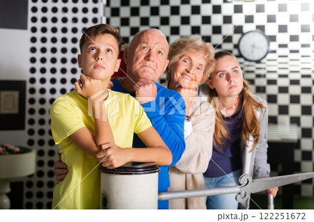 Pensive elderly grandparents together with their children solve a puzzle in quest room 122251672