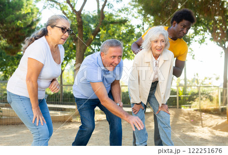 Happy casual diverse pensioners exercising together petanque in a sunny park in Spain Happy casual diverse pensioners exercising together petanque in a sunny park in Spain 122251676