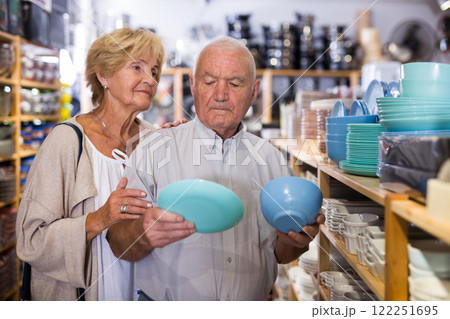 Portrait of an elderly couple in tableware store - making selection of new plates and cups Portrait of an elderly couple in tableware store - making selection of new plates and cups 122251695