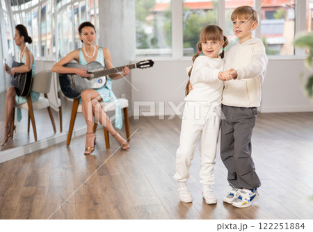Boy and girl in pair train to dance tango during classes with accompaniment of guitar Boy and girl in pair train to dance tango during classes with accompaniment of guitar 122251884