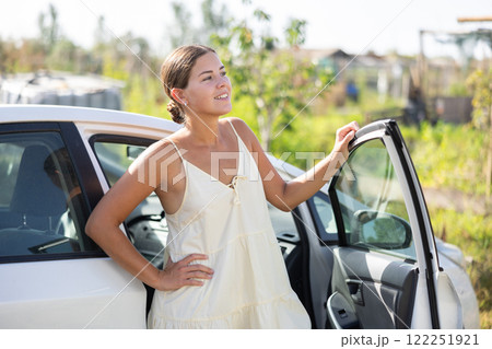 Young woman posing by car in garden Young woman posing by car in garden 122251921