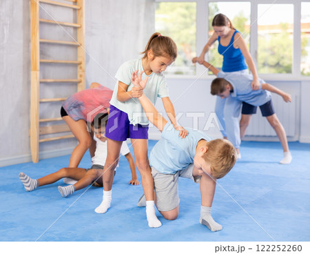 Children practicing in pair self-defence movements with female trainer supervision Children practicing in pair self-defence movements with female trainer supervision 122252260