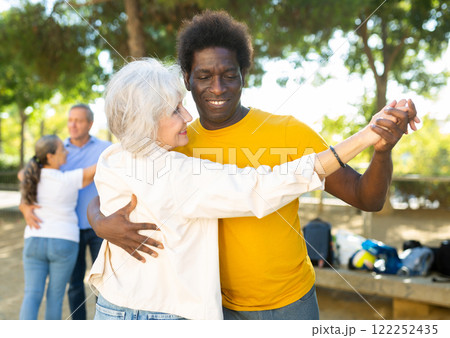 Elderly woman enjoying dance with partner in garden 122252435
