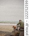 雪の日の砂浜で犬と一緒に散歩するおじいさん 122252599