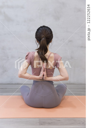 フィットネスジムで背中で合掌をする若い女性 フィットネスジムで背中で合掌をする若い女性 122252634