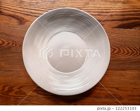 茶色いテーブルに置かれた白い皿 122253103