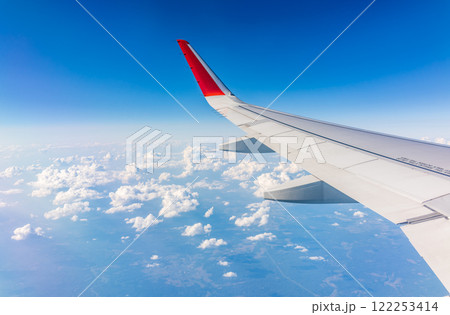 View from the airplane window at a beautiful cloudy sky and the airplane wing View from the airplane window at a beautiful cloudy sky and the airplane wing 122253414