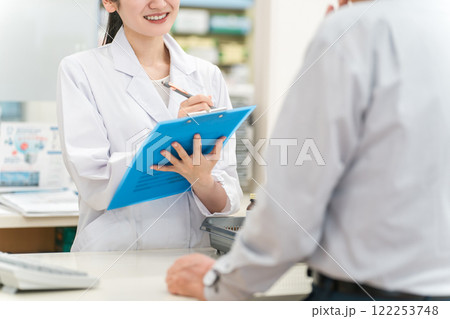 薬局のカウンターで患者をカウンセリング・ヒアリングする薬剤師の女性 薬局のカウンターで患者をカウンセリング・ヒアリングする薬剤師の女性 122253748