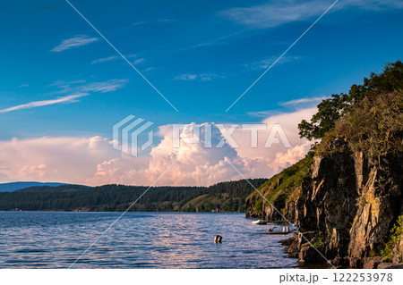 Rocky shore of a picturesque lake with beautiful cumulus clouds in the sky Rocky shore of a picturesque lake with beautiful cumulus clouds in the sky 122253978