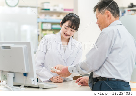 薬局で高齢者・中高年男性にスマホアプリを説明する薬剤師・調剤師の女性(服薬指導) 薬局で高齢者・中高年男性にスマホアプリを説明する薬剤師・調剤師の女性(服薬指導) 122254039