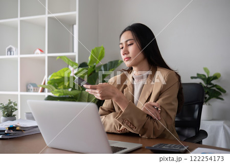 Unhappy Asian business woman shows stress over unsuccessful business while working in home office decorated with soothing green plants. 122254173