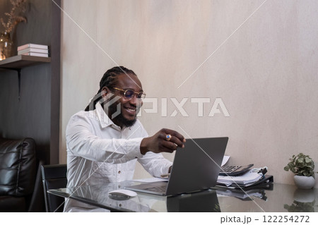 Young African American businessman spends his free time working from home on his laptop. Young African American businessman spends his free time working from home on his laptop. 122254272