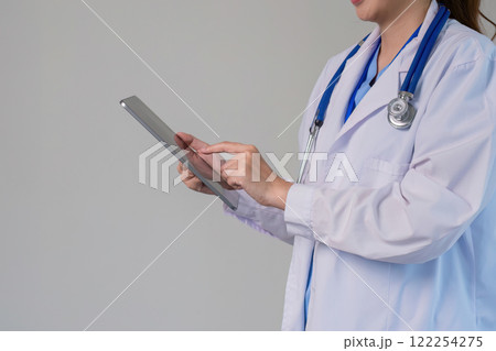 Confident Asian female doctor Standing and checking patient information on a tablet in the clinic. 122254275