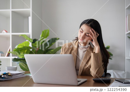 Unhappy Asian business woman shows stress over unsuccessful business while working in home office decorated with soothing green plants. Unhappy Asian business woman shows stress over unsuccessful business while working in home office decorated with soothing green plants. 122254390
