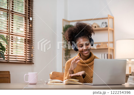 Young African Woman Relaxing at Home While Working Online with Laptop and Headphones in Cozy Living Room 122254396