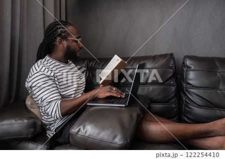 Young African American businessman spends his free time working from home on his laptop. 122254410
