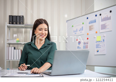 Beautiful determined business woman working using laptop and calculator calculating turnover in modern office 122254411