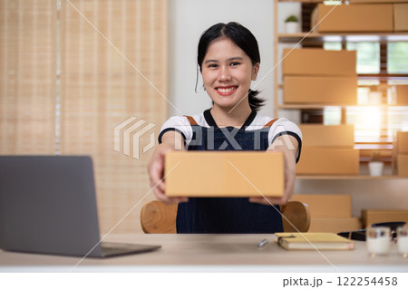 A young Asian entrepreneur sells product online through an online platform and pack product into shipping boxes. 122254458