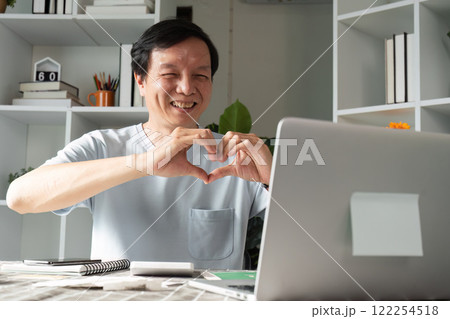 Caring professional creating a heart gesture on video call to express love from home office 122254518