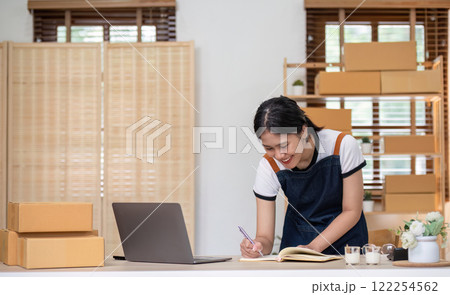 A young Asian entrepreneur sells product online through an online platform and pack product into shipping boxes. A young Asian entrepreneur sells product online through an online platform and pack product into shipping boxes. 122254562