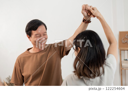 Joyful Elderly Couple Dancing Together at Home, Embracing Life and Happiness in a Warm and Cozy Setting 122254604
