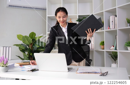Young Asian business woman in a suit is checking work on her desk in the office. 122254605
