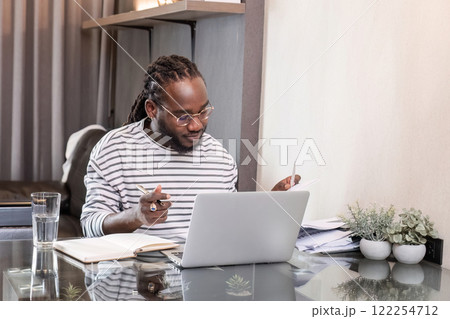 Young African American businessman spends his free time working from home on his laptop. 122254712