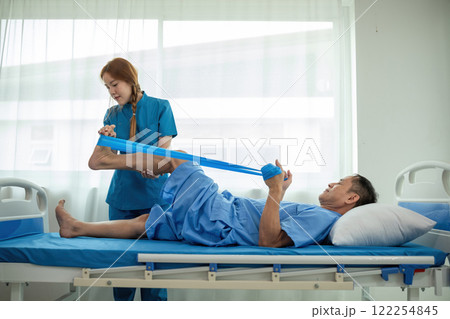 A sick caregiver or young nurse is helping a patient who is rehabilitating with physical therapy at the hospital. 122254845