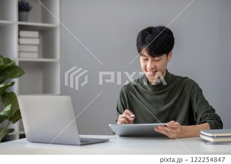 Portrait of a handsome young office worker intently studying how to do a presentation project on a laptop in his office. 122254847
