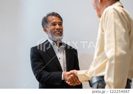 Smiling male businessman in a suit shaking hands during a successful deal negotiation 122254887