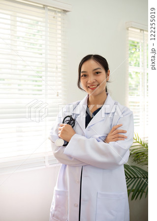 Confident female doctor Smiling woman standing holding stethoscope in clinic Confident female doctor Smiling woman standing holding stethoscope in clinic 122255019