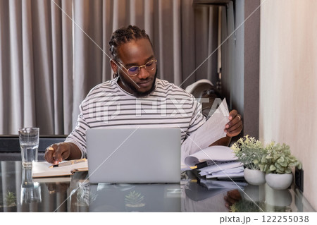 Young African American businessman spends his free time working from home on his laptop. 122255038