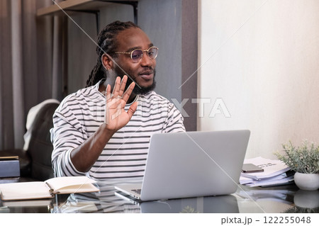 Young African American businessman spends his weekend working from home using his laptop in the living room. 122255048