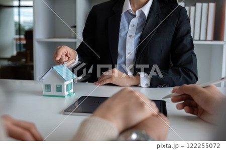 A real estate agent or insurance agent presents a house plan and insurance contract to an Asian couple. 122255072