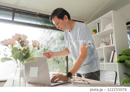 Middle-aged man shopping online and enjoying a productive moment at home office 122255078