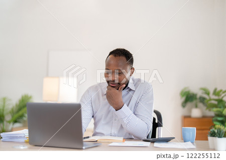 African American businessman working with laptop Take notes on documents in the office and prepare performance analysis reports. African American businessman working with laptop Take notes on documents in the office and prepare performance analysis reports. 122255112