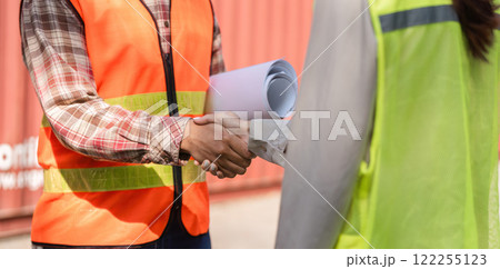 Construction professionals shaking hands on-site, discussing project plans and collaboration 122255123