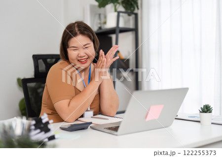 Happy Young Woman Analyzing Financial Documents at Home Office with Laptop and Notepad Happy Young Woman Analyzing Financial Documents at Home Office with Laptop and Notepad 122255373