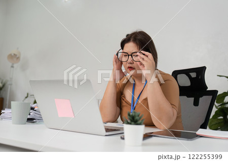 Stressed Businesswoman at Work Desk with Laptop and Papers in Modern Office Environment Stressed Businesswoman at Work Desk with Laptop and Papers in Modern Office Environment 122255399