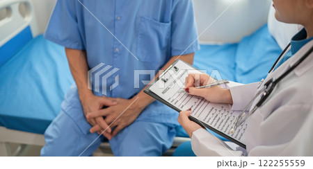 A female doctor is examining the body and taking notes on a sick person in a hospital examination room. 122255559