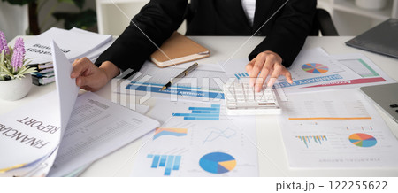 Asian female accountant Use a calculator to calculate business numbers on a white wooden table in the office. Asian female accountant Use a calculator to calculate business numbers on a white wooden table in the office. 122255622
