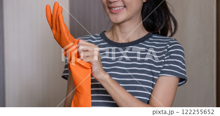 Closeup, beautiful young housekeeper wearing orange rubber gloves getting ready for cleaning. 122255652