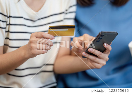 Mother and Child Enjoying Online Shopping Together Using a Smartphone and Credit Card in a Cozy Home Setting Mother and Child Enjoying Online Shopping Together Using a Smartphone and Credit Card in a Cozy Home Setting 122255656