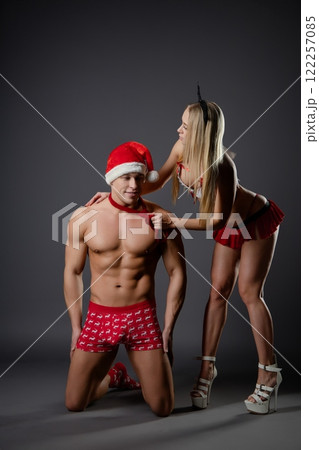 Couple engages in playful roleplay with festive attire in indoor setting Couple engages in playful roleplay with festive attire in indoor setting 122257085