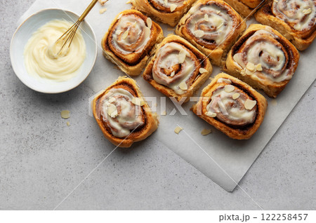 Freshly baked cinnamon rolls topped with cream cheese frosting and almond slivers 122258457