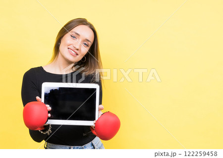 Businesswoman in a studio sat wearing boxing gloves, yellow background 122259458
