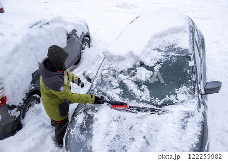 Person Clearing Snow from Car in Winter Landscape Person Clearing Snow from Car in Winter Landscape 122259982