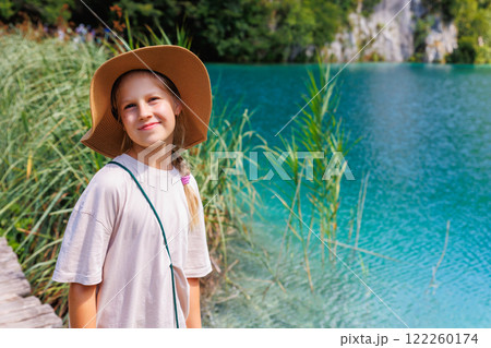 Portrait little cute adorable blond kid girl wear straw hat enjoy hiking Plitvice lakes national park landscape Croatia sunny summer day. Kid explore nature. Happy girl hobby activities 122260174