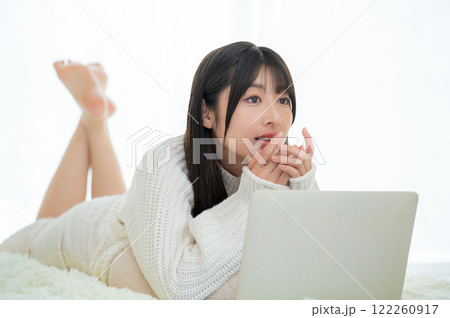 うつ伏せに寝てパソコンを操作する日本人女性 122260917